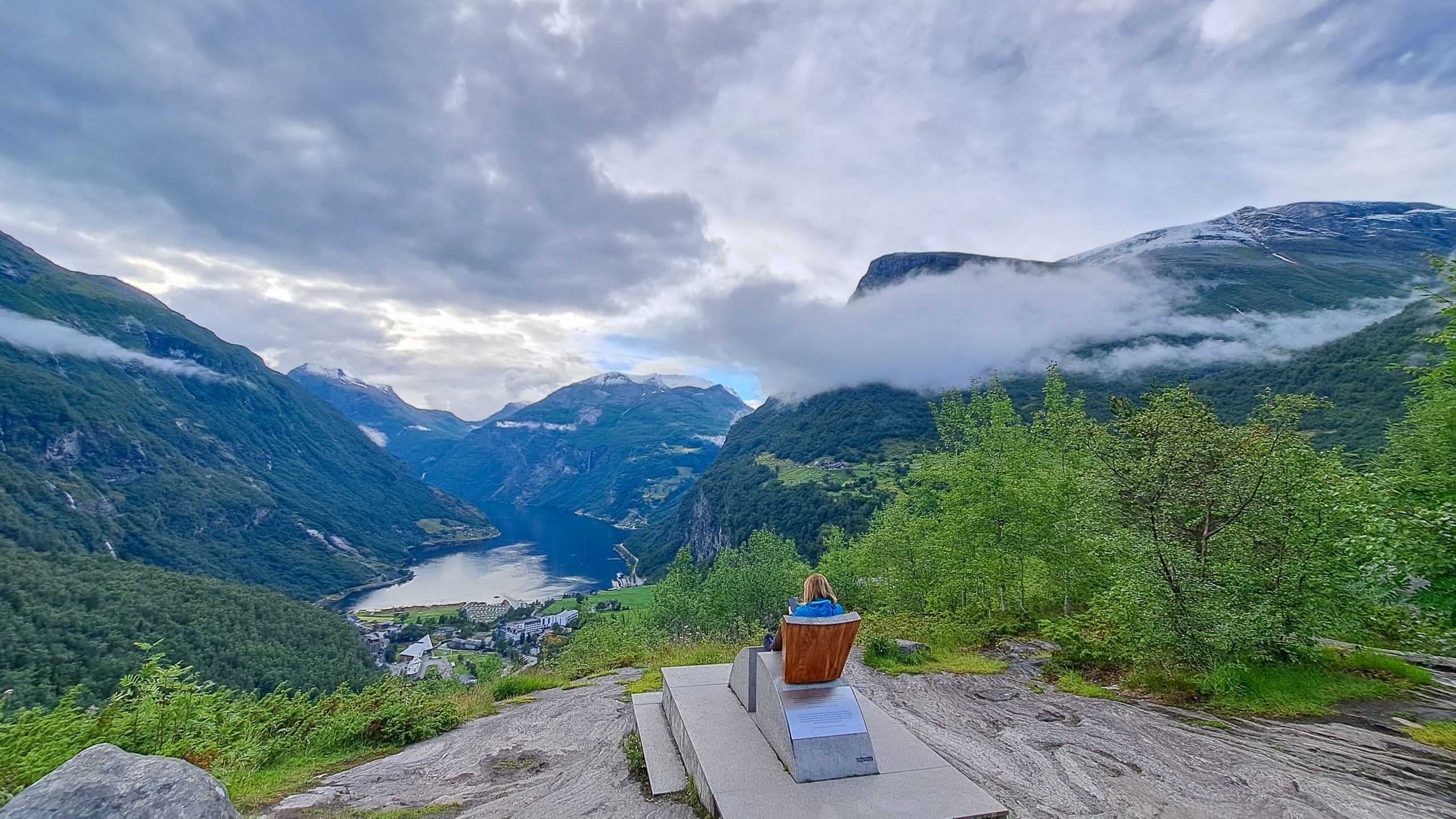 A woman on the princess chair in Fjydalsjuvet, great view of mountains, sea, clouds, sky over Geirangerfjord